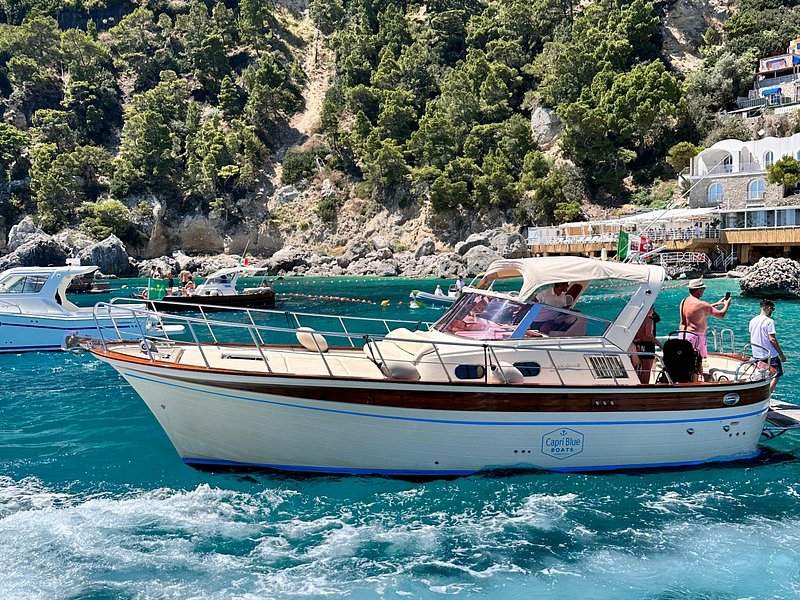 Motor boats moored below a cliffside village on the Capri shore