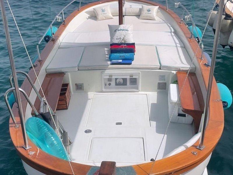 The open foredeck of a traditional Capri gozzo, cushions laid out and nobody aboard