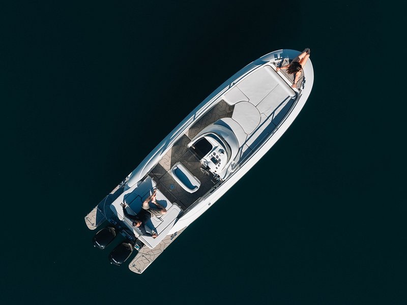 A motor yacht photographed from directly above on flat deep-blue water