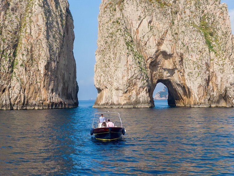 A boat passing beneath the arch through Faraglione di Mezzo